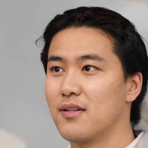 Joyful asian young-adult male with short  black hair and brown eyes