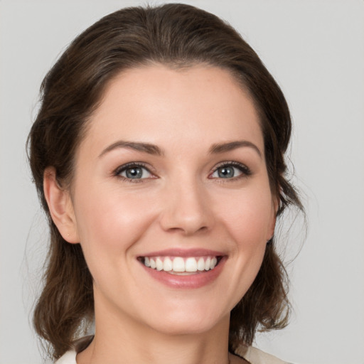 Joyful white young-adult female with medium  brown hair and grey eyes