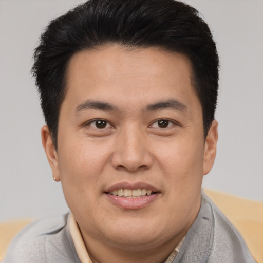 Joyful asian young-adult male with short  brown hair and brown eyes