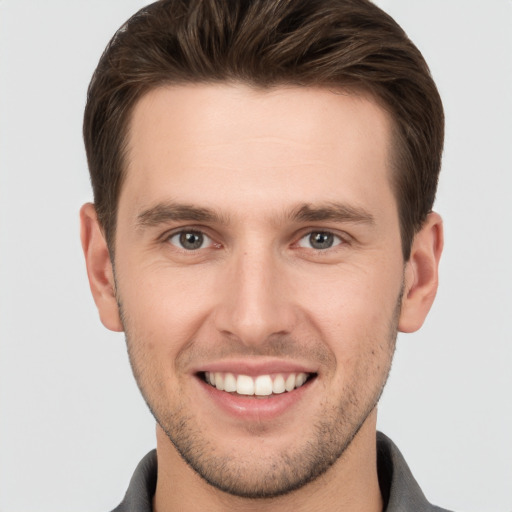 Joyful white young-adult male with short  brown hair and grey eyes