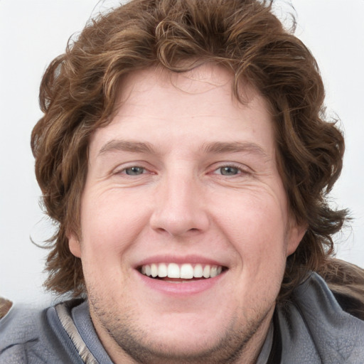 Joyful white young-adult male with medium  brown hair and blue eyes