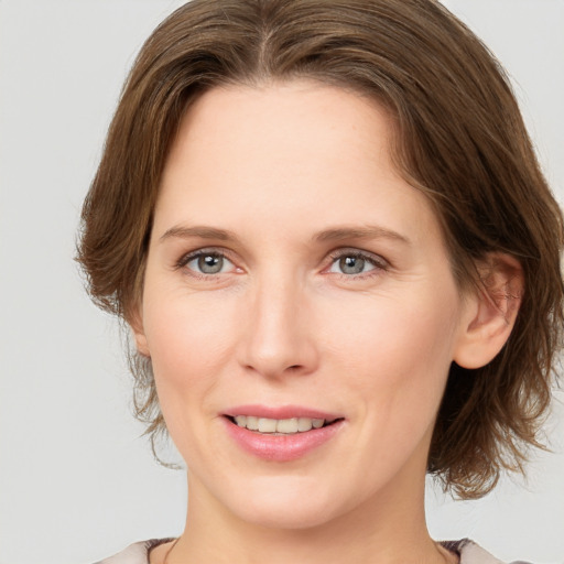 Joyful white young-adult female with medium  brown hair and grey eyes