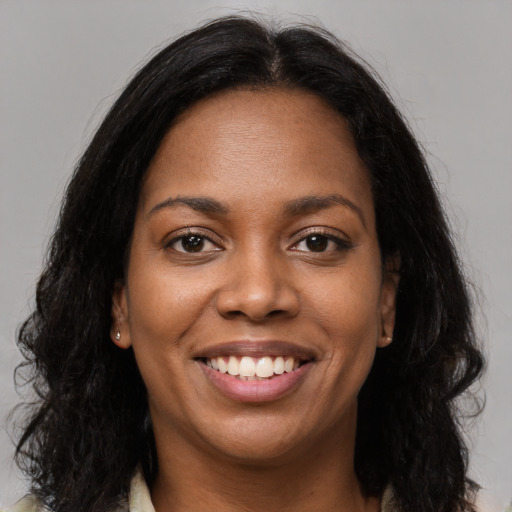 Joyful black young-adult female with long  brown hair and brown eyes