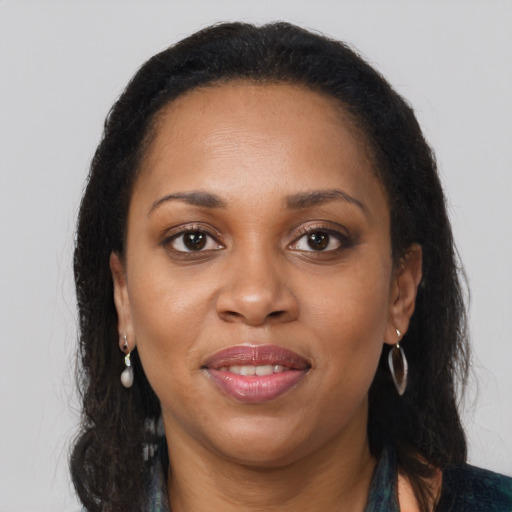 Joyful black young-adult female with long  brown hair and brown eyes