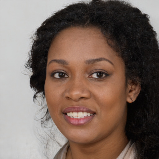 Joyful black young-adult female with long  black hair and brown eyes