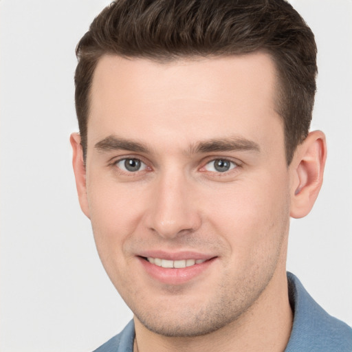 Joyful white young-adult male with short  brown hair and grey eyes