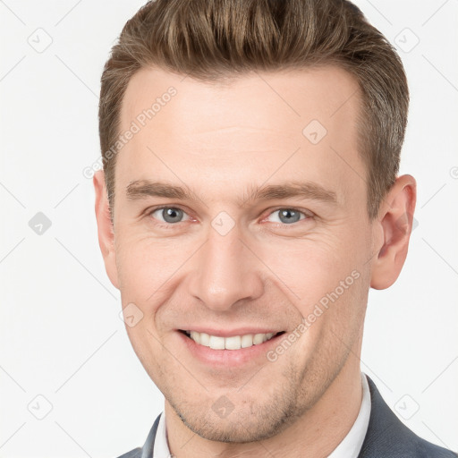 Joyful white young-adult male with short  brown hair and grey eyes