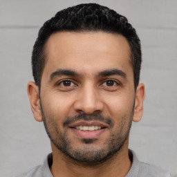 Joyful latino young-adult male with short  black hair and brown eyes