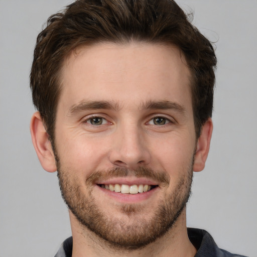 Joyful white young-adult male with short  brown hair and grey eyes