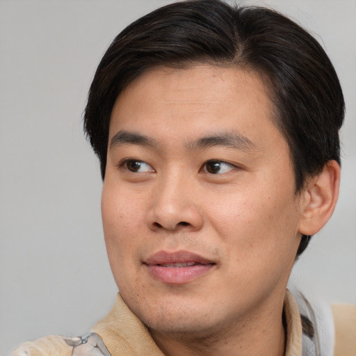 Joyful asian young-adult male with short  brown hair and brown eyes