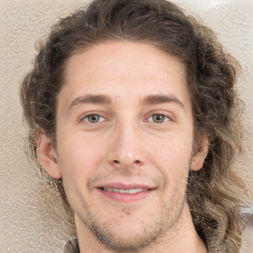 Joyful white young-adult male with long  brown hair and grey eyes