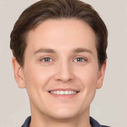 Joyful white young-adult male with short  brown hair and grey eyes