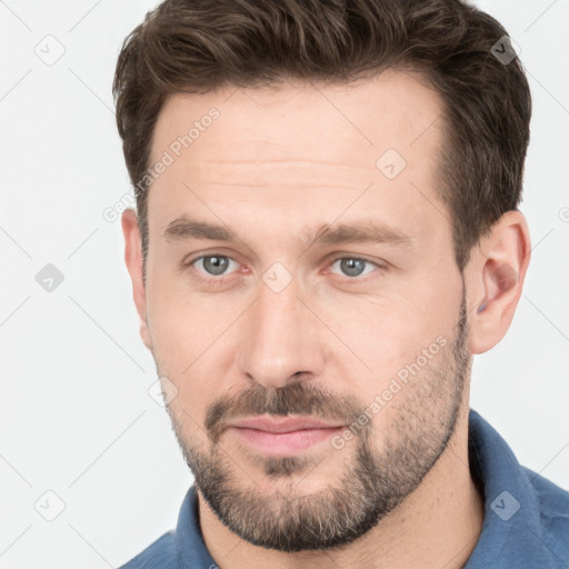 Joyful white young-adult male with short  brown hair and grey eyes