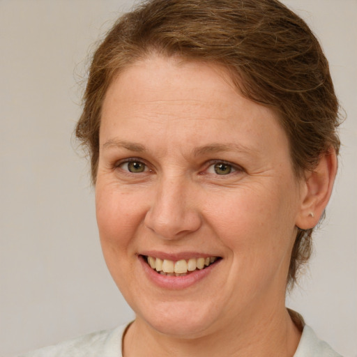 Joyful white adult female with medium  brown hair and green eyes