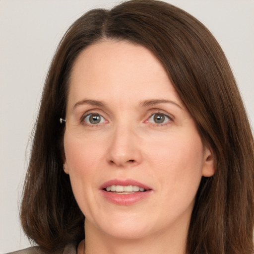 Joyful white adult female with long  brown hair and grey eyes