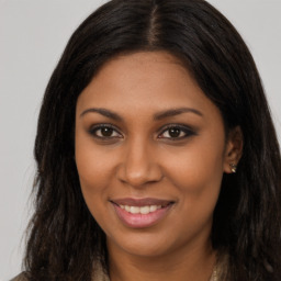 Joyful black young-adult female with long  brown hair and brown eyes