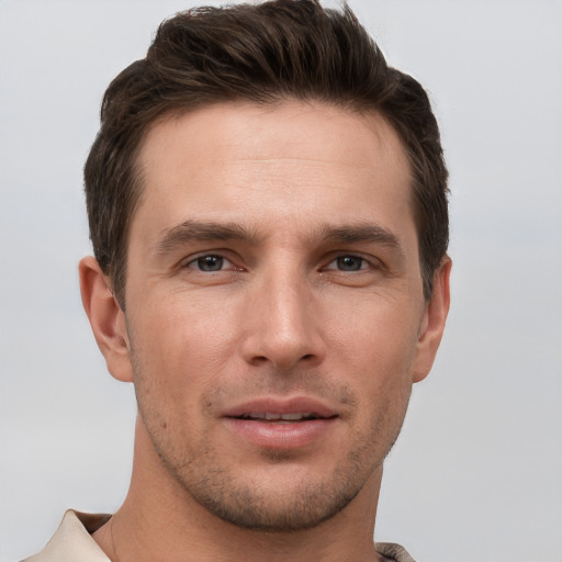 Joyful white young-adult male with short  brown hair and grey eyes