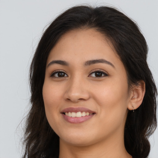 Joyful latino young-adult female with long  brown hair and brown eyes