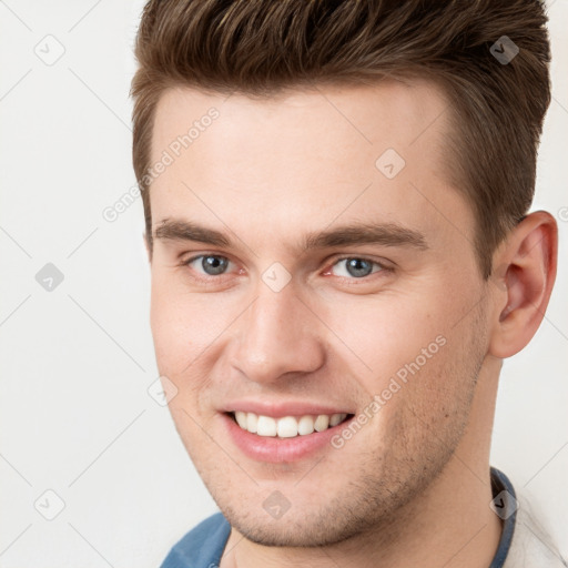 Joyful white young-adult male with short  brown hair and grey eyes