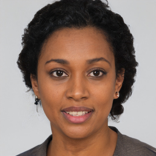 Joyful black young-adult female with short  black hair and brown eyes