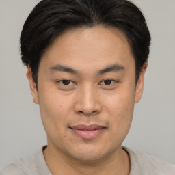 Joyful asian young-adult male with short  brown hair and brown eyes