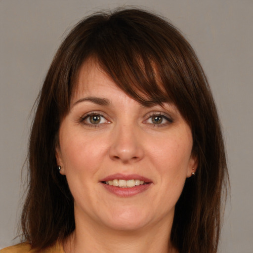 Joyful white adult female with medium  brown hair and blue eyes