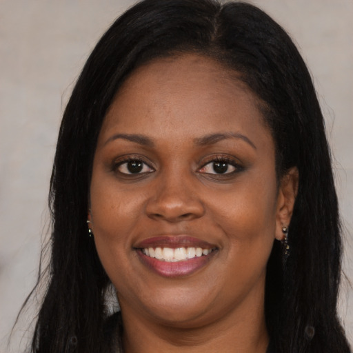 Joyful black young-adult female with long  brown hair and brown eyes