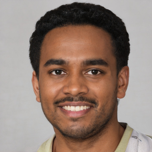 Joyful black young-adult male with short  black hair and brown eyes