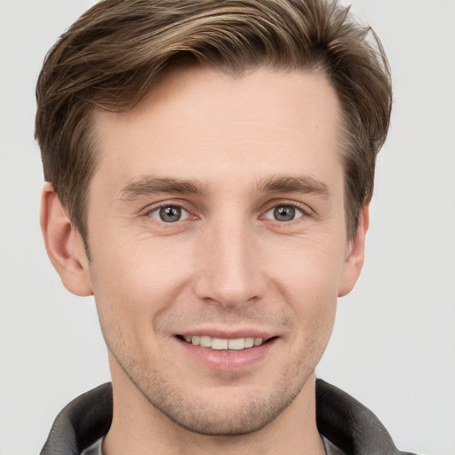 Joyful white young-adult male with short  brown hair and grey eyes