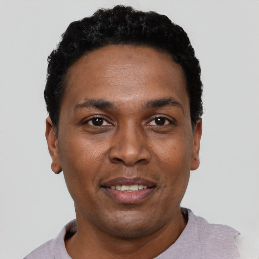 Joyful black young-adult male with short  black hair and brown eyes