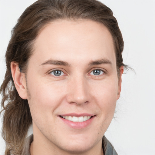 Joyful white young-adult male with long  brown hair and grey eyes