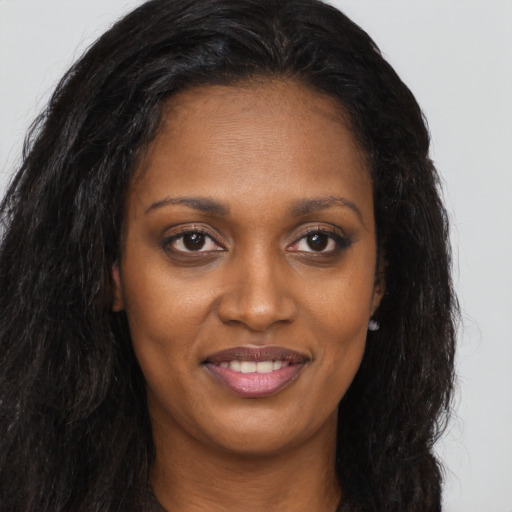 Joyful black young-adult female with long  brown hair and brown eyes