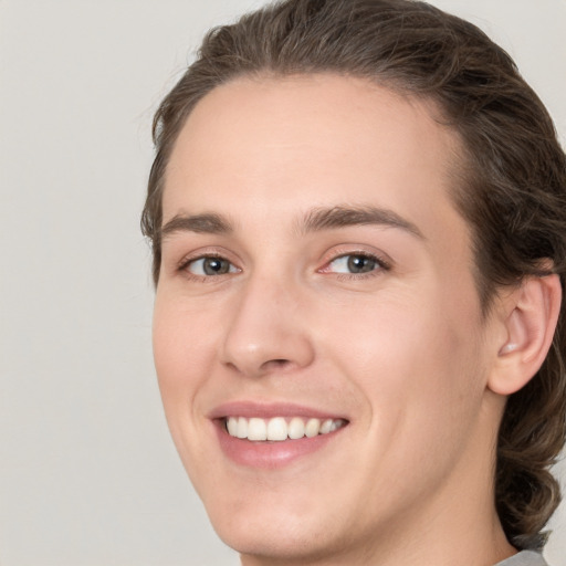 Joyful white young-adult male with medium  brown hair and grey eyes