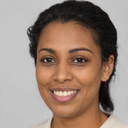 Joyful black young-adult female with long  brown hair and brown eyes