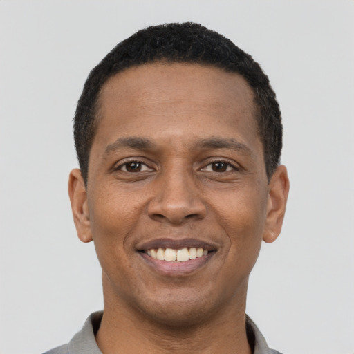 Joyful black young-adult male with short  black hair and brown eyes