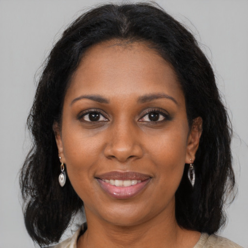 Joyful black young-adult female with long  brown hair and brown eyes