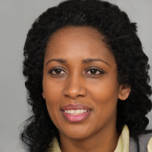 Joyful black young-adult female with long  black hair and brown eyes