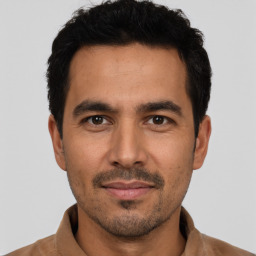 Joyful latino young-adult male with short  black hair and brown eyes