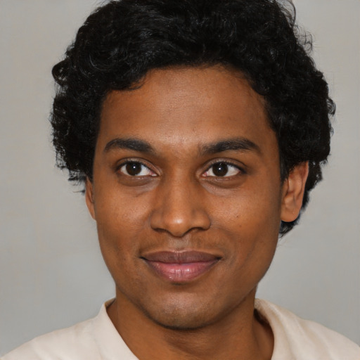 Joyful black young-adult male with short  brown hair and brown eyes