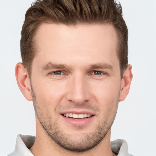 Joyful white young-adult male with short  brown hair and grey eyes