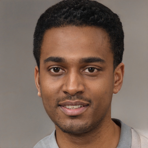 Joyful black young-adult male with short  black hair and brown eyes