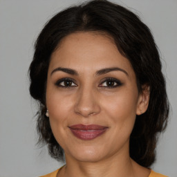 Joyful latino adult female with medium  brown hair and brown eyes