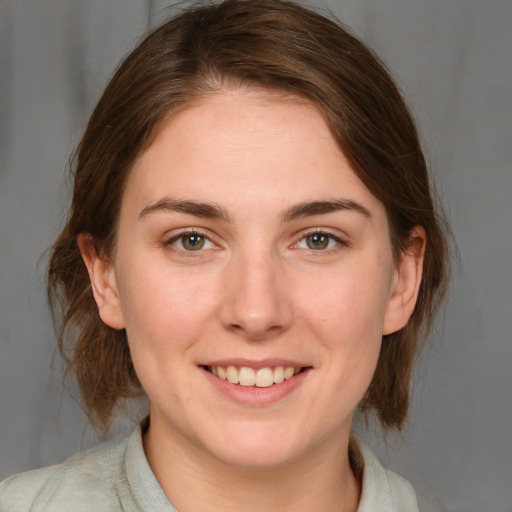 Joyful white young-adult female with medium  brown hair and grey eyes