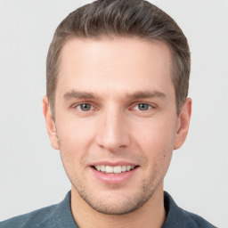 Joyful white young-adult male with short  brown hair and grey eyes