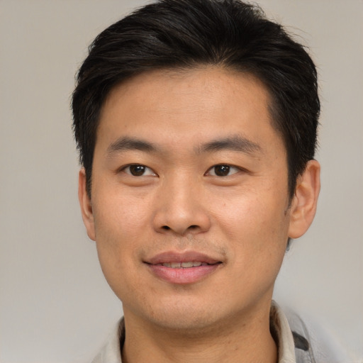 Joyful asian young-adult male with short  brown hair and brown eyes