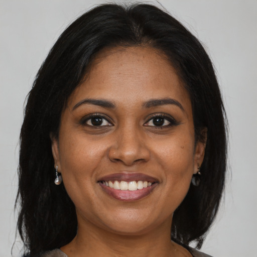 Joyful black adult female with long  brown hair and brown eyes