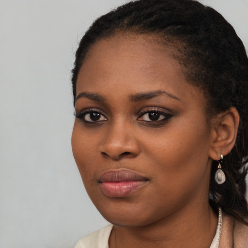 Joyful black young-adult female with long  brown hair and brown eyes