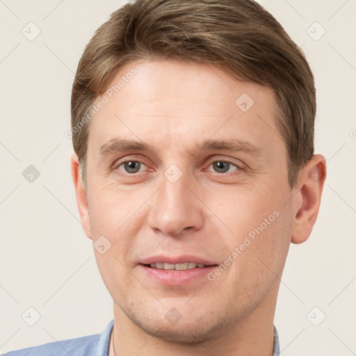 Joyful white young-adult male with short  brown hair and grey eyes