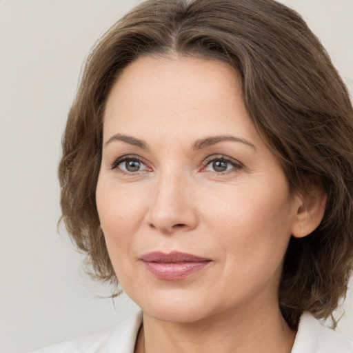 Joyful white adult female with medium  brown hair and grey eyes