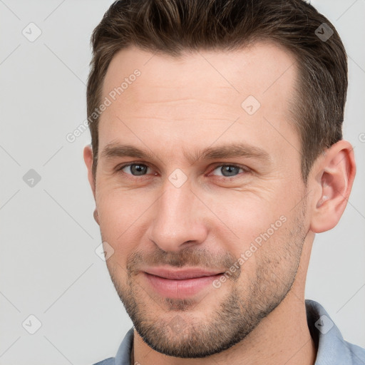 Joyful white young-adult male with short  brown hair and grey eyes